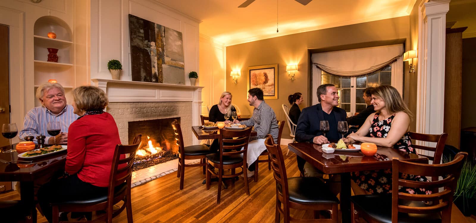 A man and a woman have dinner in a restaurant by a fireplace