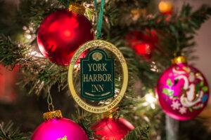 Christmas ornament with a gold oval with green York Harbor Inn sign in the middle.